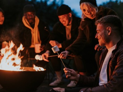 Friends enjoying s'mores and marshmellow together by the bonfire